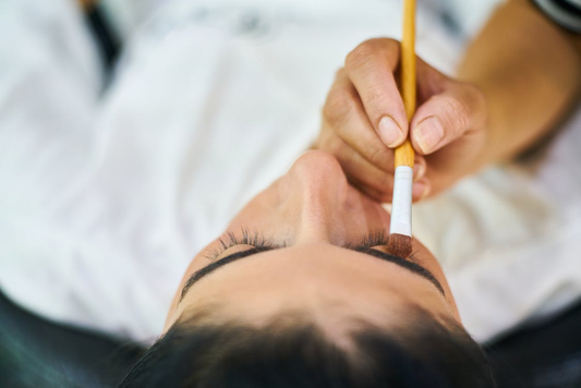 Person holding a makeup brush over a client’s eyes